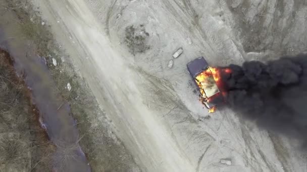 Вид зверху на сіре поле, де величезний вогонь повністю спалює автомобіль і чорний дим піднімається вгору — стокове відео