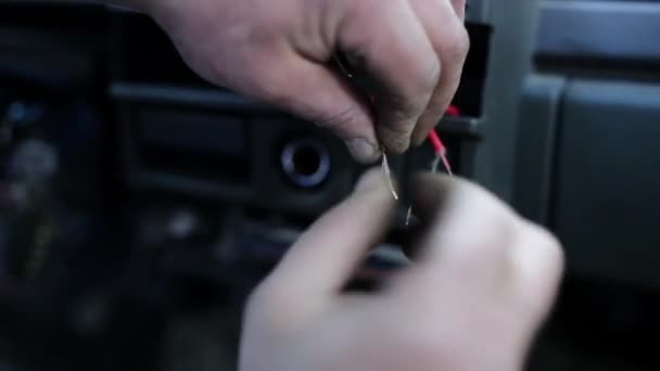 자동차에 두 개의 벌거 벗은 빨간 케이블을 연결하고 묶으려고하는 사람의 손의 매크로 보기. — 비디오