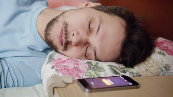 Man with dark hair lays on bed with comfy pillow, wakes up and looks at phone — Stock Video