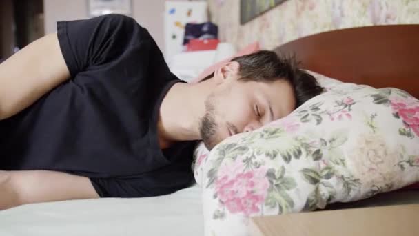 Hombre con el pelo oscuro cae en la cama con almohada cómoda e inmediatamente se duerme . — Vídeos de Stock