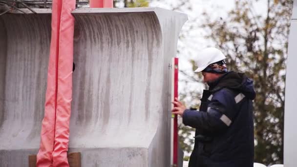 SAINT PETERSBURG, RÚSSIA - SETEMBRO 20, 2018: Trabalhador de capacete uniforme e branco faz medições com equilíbrio no concreto — Vídeo de Stock