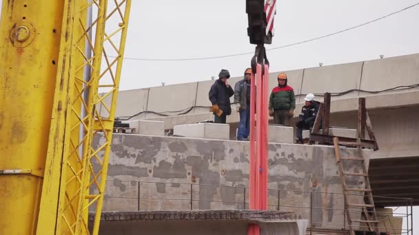 俄罗斯圣彼得堡 - 2018年9月20日:桥梁施工区,男工人行走,混凝土梁由起重机移动 — 图库视频影像