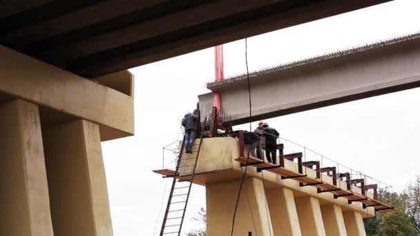 SAINT PETERSBURG, RUSIA - 20 SEPTEMBRIE 2018: Trei muncitori de sex masculin fac ceva sub o imensă grindă de beton ridicată . — Videoclip de stoc