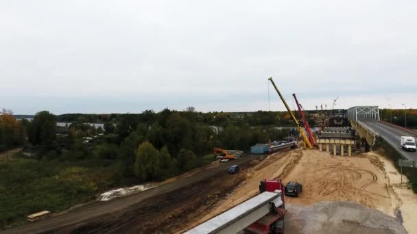 Sankt Petersburg, Rosja-20 września, 2018: Sky widok na budowę mostu z dwóch dźwigów w pobliżu jezdnia i pole — Wideo stockowe