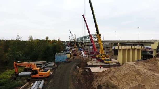Petrohrad, Rusko-20. září 2018: Drone pohled na stavbu mostu se dvěma jeřáby poblíž silnice a polní — Stock video