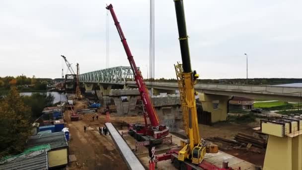 Sint-Petersburg, Rusland-20 september 2018: luchtfoto van brug bouw gebied met twee kranen in de buurt van de weg en het veld — Stockvideo