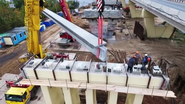 SAN PETERSBURG, RUSIA - 20 DE SEPTIEMBRE DE 2018: Grúas elevan viga de hormigón y puente área de construcción cercana carretera y río — Vídeos de Stock