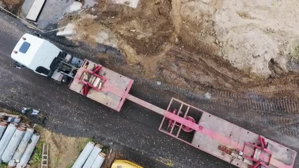 SAN PETERSBURG, RUSIA - 20 DE SEPTIEMBRE DE 2018: Vista del cielo de un camión blanco en movimiento con un largo remolque rojo en la zona de construcción — Vídeos de Stock