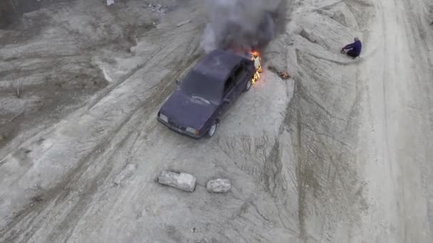 El coche está ardiendo con gran llama en el desierto campo de polvo rodeado de árboles vacíos . — Vídeos de Stock