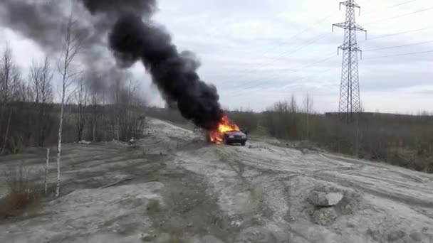 Verlaten grijs veld waar enorme vlam volledig Burns auto en zwarte rook omhoog gaat — Stockvideo