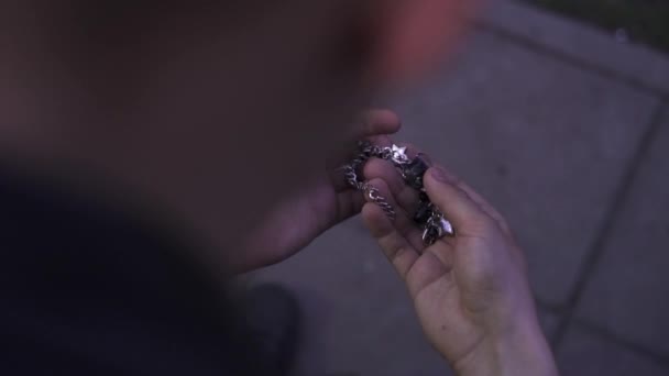 Slim guy is holding in hand nice womans bracelet standing in street in evening — Stock Video