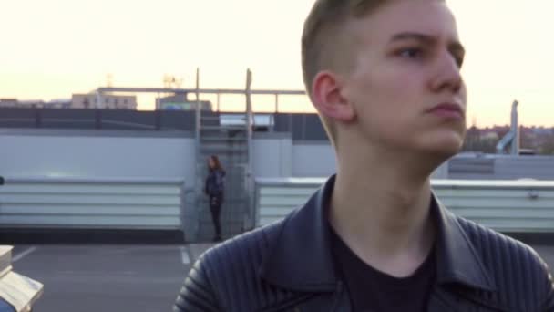 Cute young male with nice blond haircut in jacket stands outside and smiles. — Stock Video