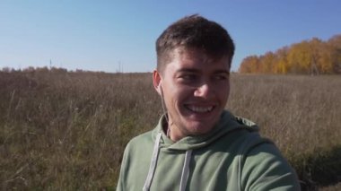 Ağzı saplı gülümseyen genç adam kırsal alanda yürüyor..