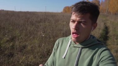 Ağızda sapı olan çekici genç adam kırsal alanda yürüyor..