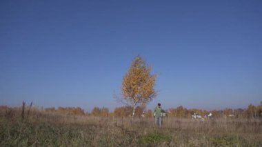 Beyaz bir gencin ağaçların altında dikilirken görüntüsü kırsal kesimde sarı yapraklarla.