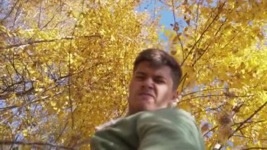 Kırsal kesimde sarı yapraklarla ağaçların altında duran yakışıklı bir adam..