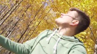 Kırsal kesimde sarı yapraklarla ağaçların altında duran çekici bir adam..