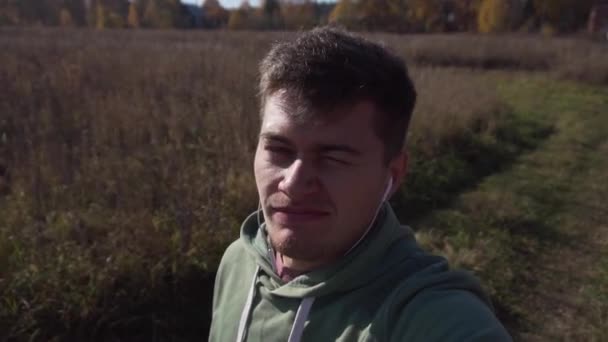 Jovem caucasiano atraente está andando no campo sozinho ao longo dos campos . — Vídeo de Stock