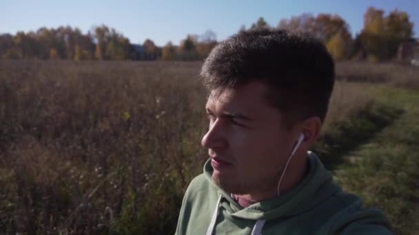 Красивий кавказький молодий хлопець йде в сільській місцевості один уздовж полів . — стокове відео