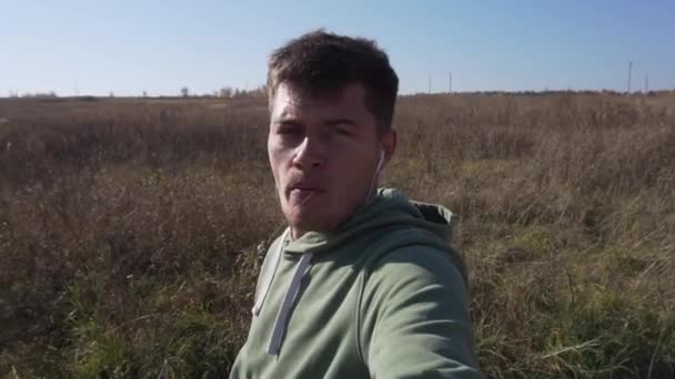 Ağzı saplı yakışıklı beyaz adam tarla boyunca kırsalda yürüyor.. — Stok video