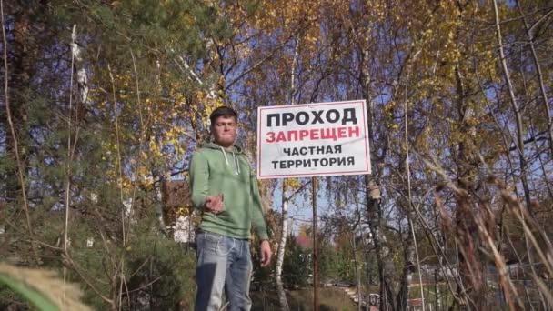 Fiatal férfi kapucnis áll mellett nagy tábla Korlátozott terület, Magántulajdon. — Stock videók