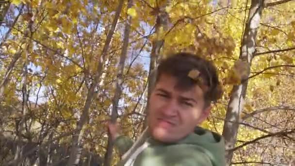 View of white young man standing under trees with yellow leaves in countryside. — ストック動画