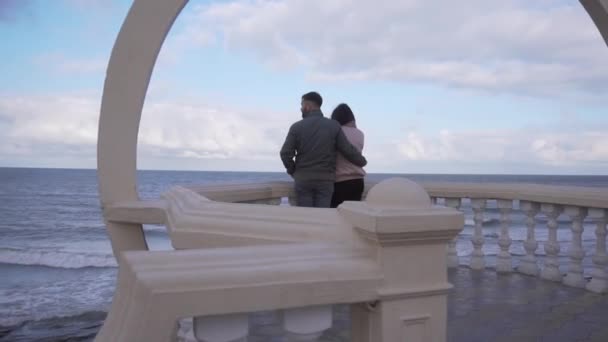 Hombre y mujer de pie en la plataforma de observación y mirar la costa vacía y las olas . — Vídeo de stock