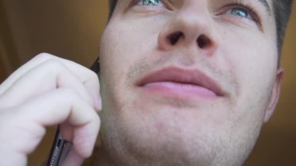 Rosto de homem caucasiano bonito em t-shirt escura e olhos azuis, falando no smartphone — Vídeo de Stock