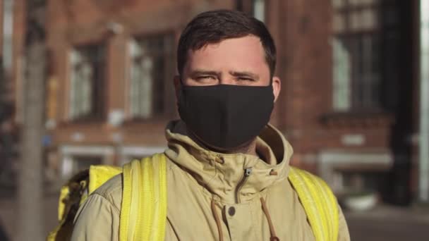 Caucasian Male Delivery Man Black Mask Jacket Yellow Backpack Turns — Stock Video