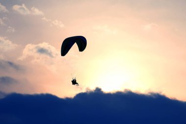 Bir kanat karşı batan güneşin gökyüzünde uçan yamaçparaşütü