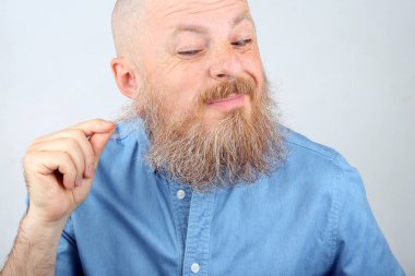 Sakalını mavi kot tişörtlü adam dokunur