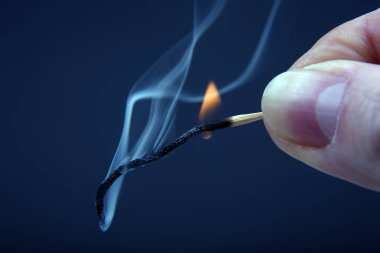 Koyu arka plan üzerinde elinde yanan ve ahşap Sigara maç