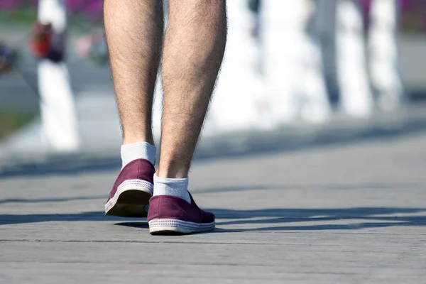 the feet of the man walking on the wooden bridge