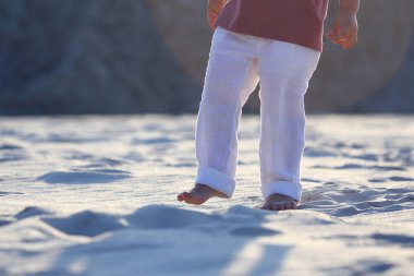bir çocuğun Beyaz pantolonlu kum üzerinde çıplak ayak
