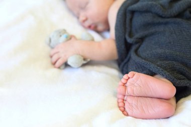Yeni doğmuş bebek bir oyuncağın kollarında uyuyor.