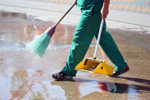 Temizlikçi şehrin kaldırımını temizliyor. 