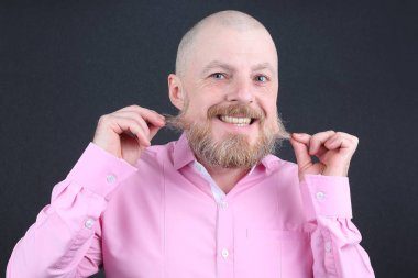 Pembe gömlekli sakallı adam sakalını dokunur