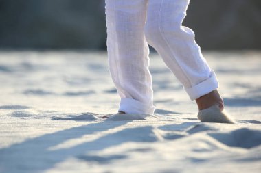 bir çocuğun Beyaz pantolonlu kum üzerinde çıplak ayak