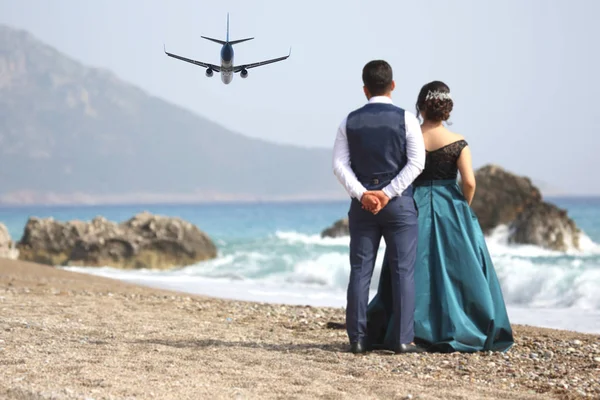 男人和一个女人看着在海滩上起飞的乘客飞机 — 图库照片