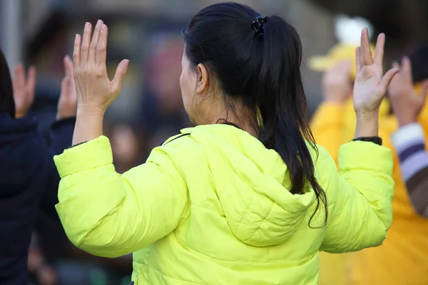 Woman in yellow jacket with hands u