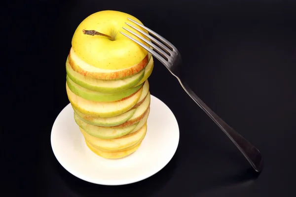 Apple cut into pieces on a white saucer with a fork