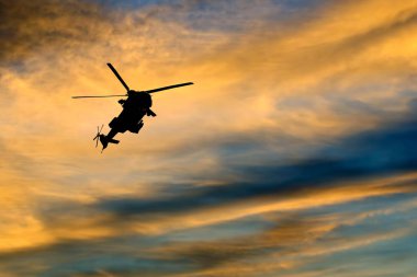 Karşı parlak akşam gökyüzünde uçan bir helikopter silüeti
