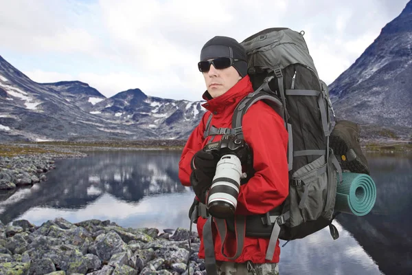 traveler photographer in the red jacket on the mountain slope