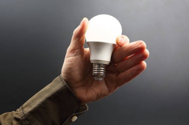 Koyu arka plan üzerinde insan elinde yeni LED lamba dahildir