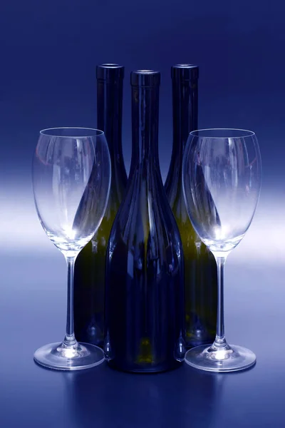 Tři prázdných lahví od vína a dvě prázdné sklenice na víno — Stock fotografie