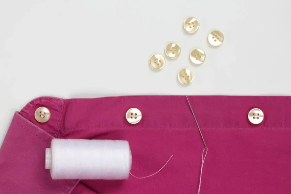 Nål med vita trådar och sydda pärlemorknappar på tröjan — Stockfoto