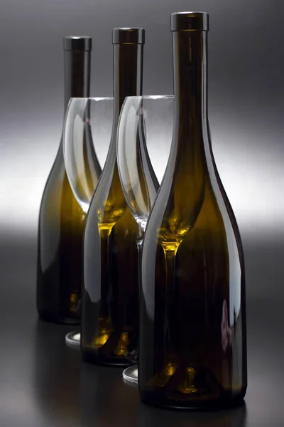 Üç şarap şişeleri ve iki boş şarap gözlük yakın çekim — Stok fotoğraf