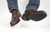 Férfi láb farmer és barna klasszikus cipő fehér háttere