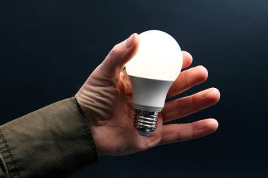 Koyu arka plan üzerinde insan elinde yeni LED lamba dahildir
