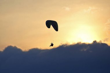 Bir kanat karşı batan güneşin gökyüzünde uçan yamaçparaşütü